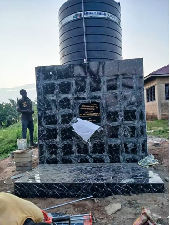 The dedication plaque and 7,000-litre water tank of the completed borehole project
