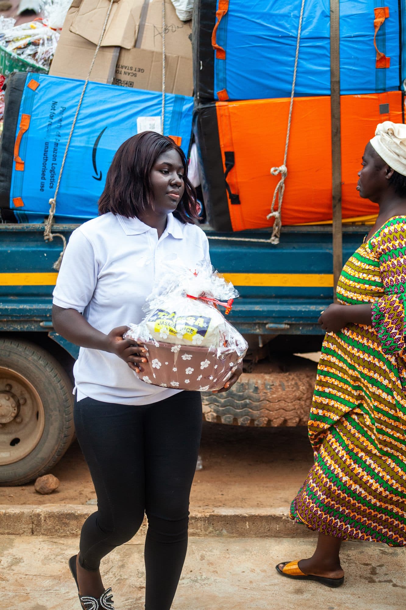 A volunteer carrying a wrapped gift hamper beside the delivery truck