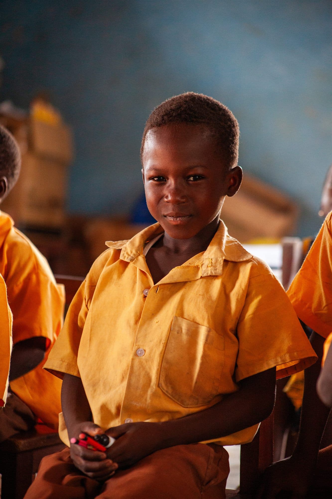 A schoolboy in a yellow uniform holding his newly donated bag
