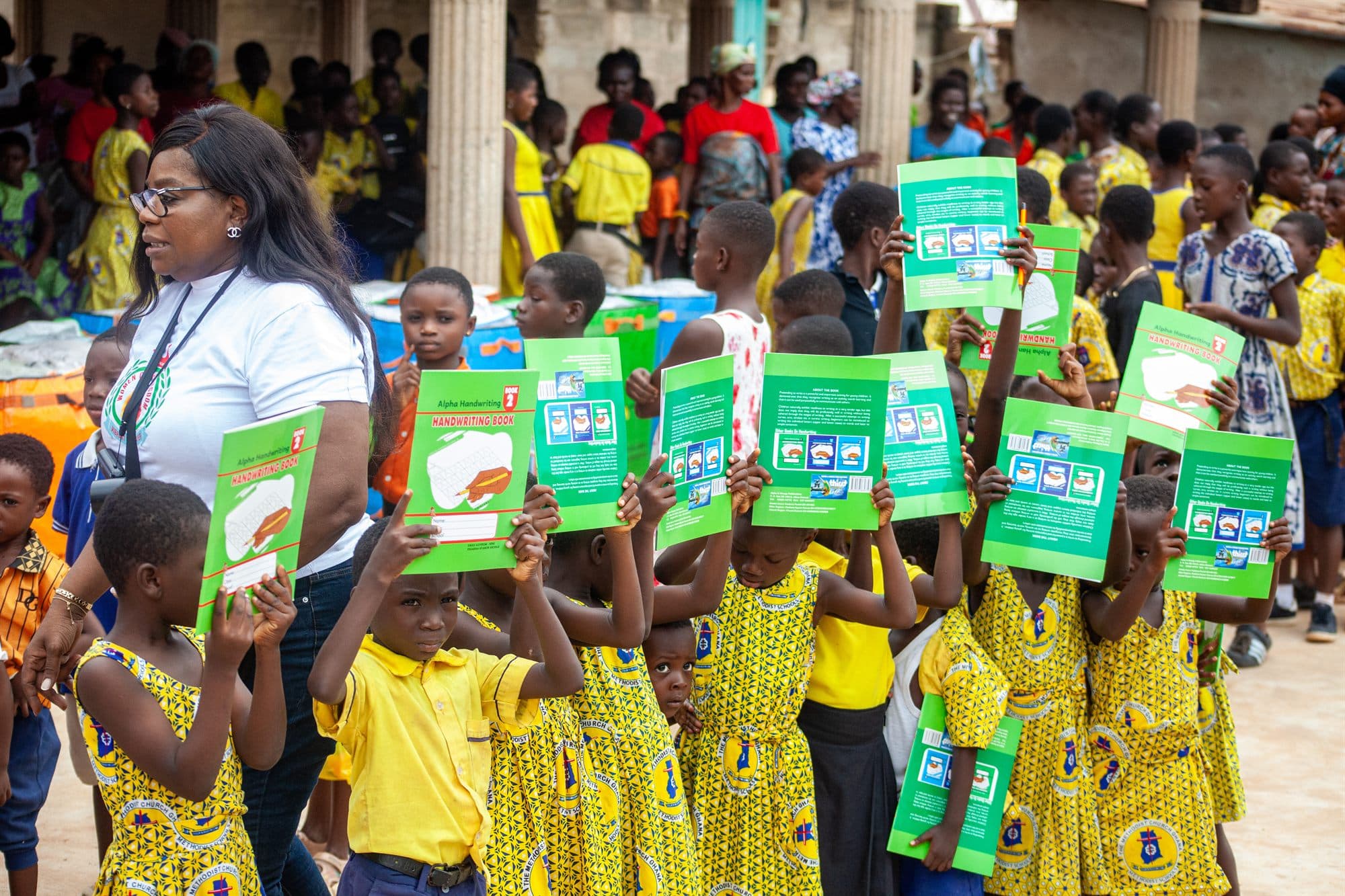 Schoolchildren holding up newly donated handwriting books at a distribution