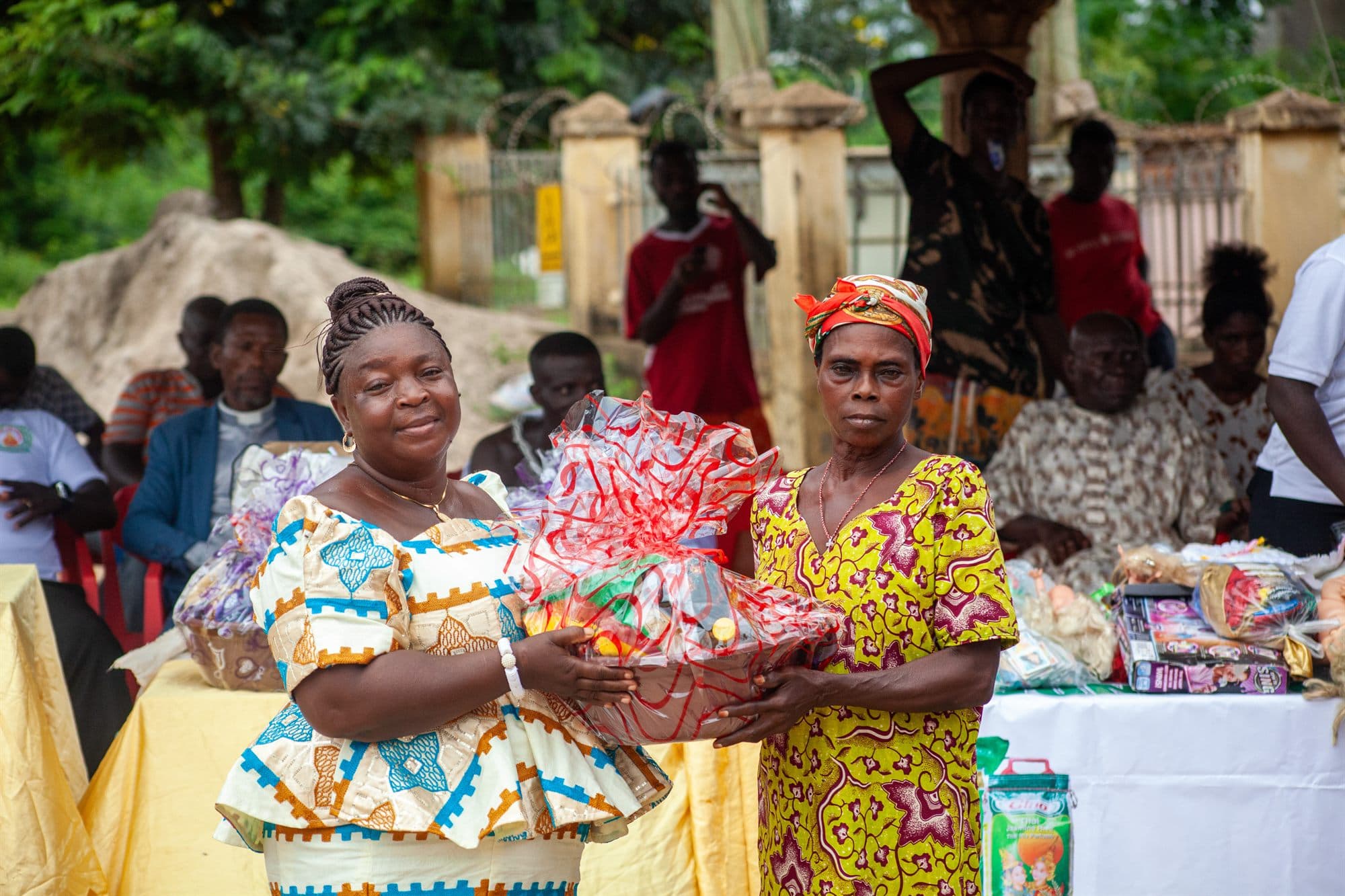 A Women of the Kingdom volunteer handing a wrapped gift hamper to a community member
