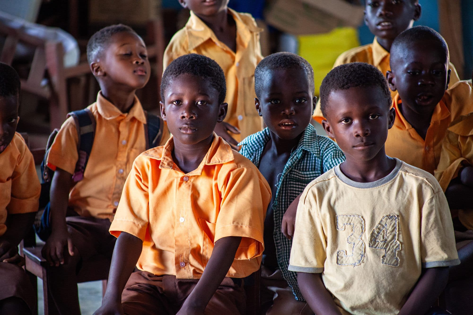 Schoolchildren in orange uniforms seated together during a Women of the Kingdom school visit