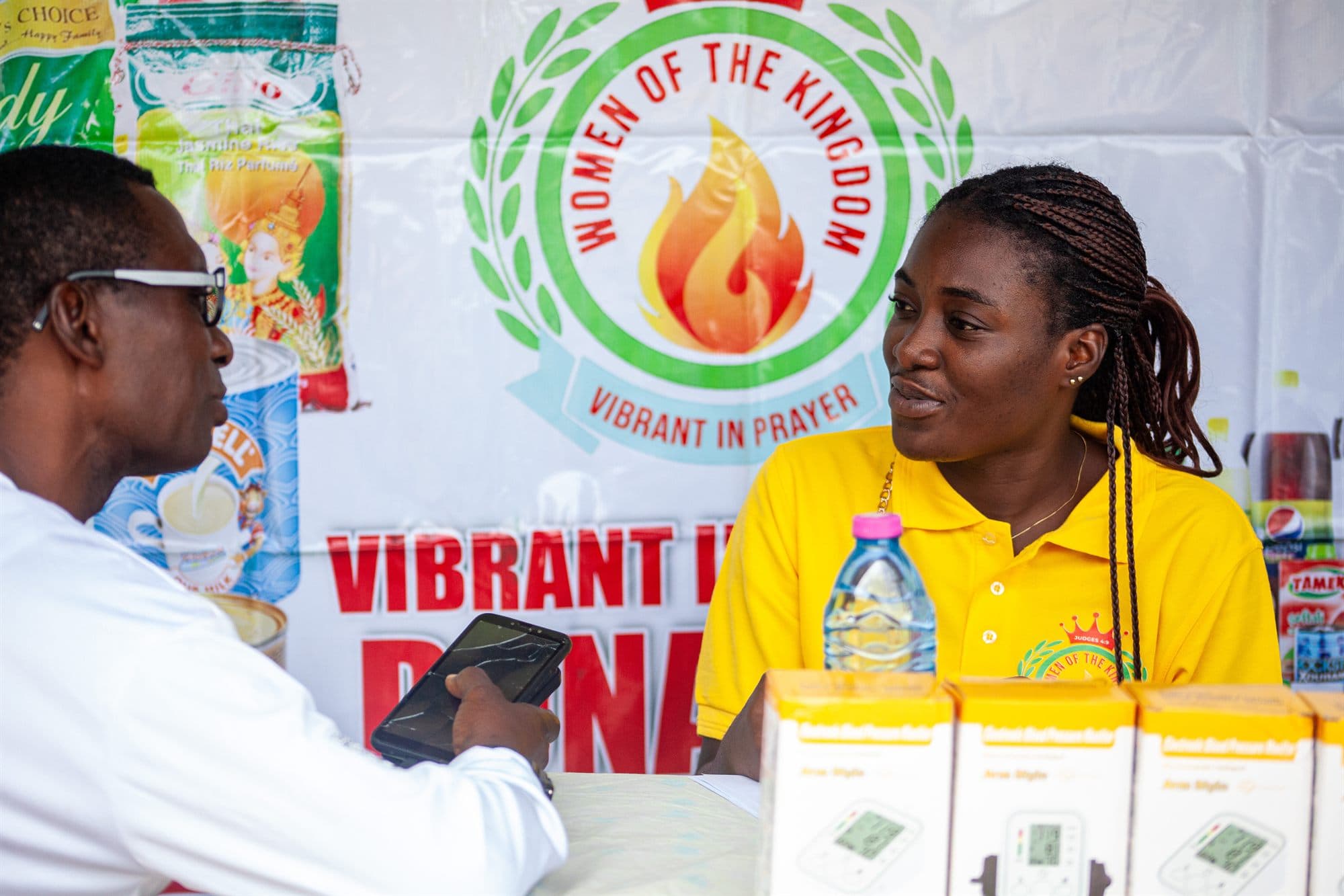 A Women of the Kingdom volunteer assisting a community member at an outreach stand